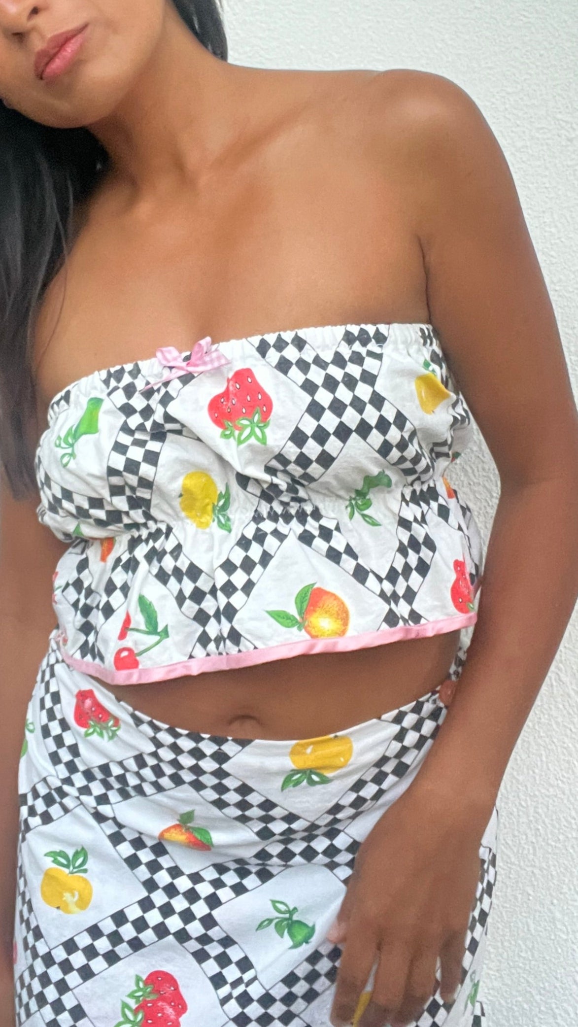 Woman wearing a patterned strapless top and skirt against a white background