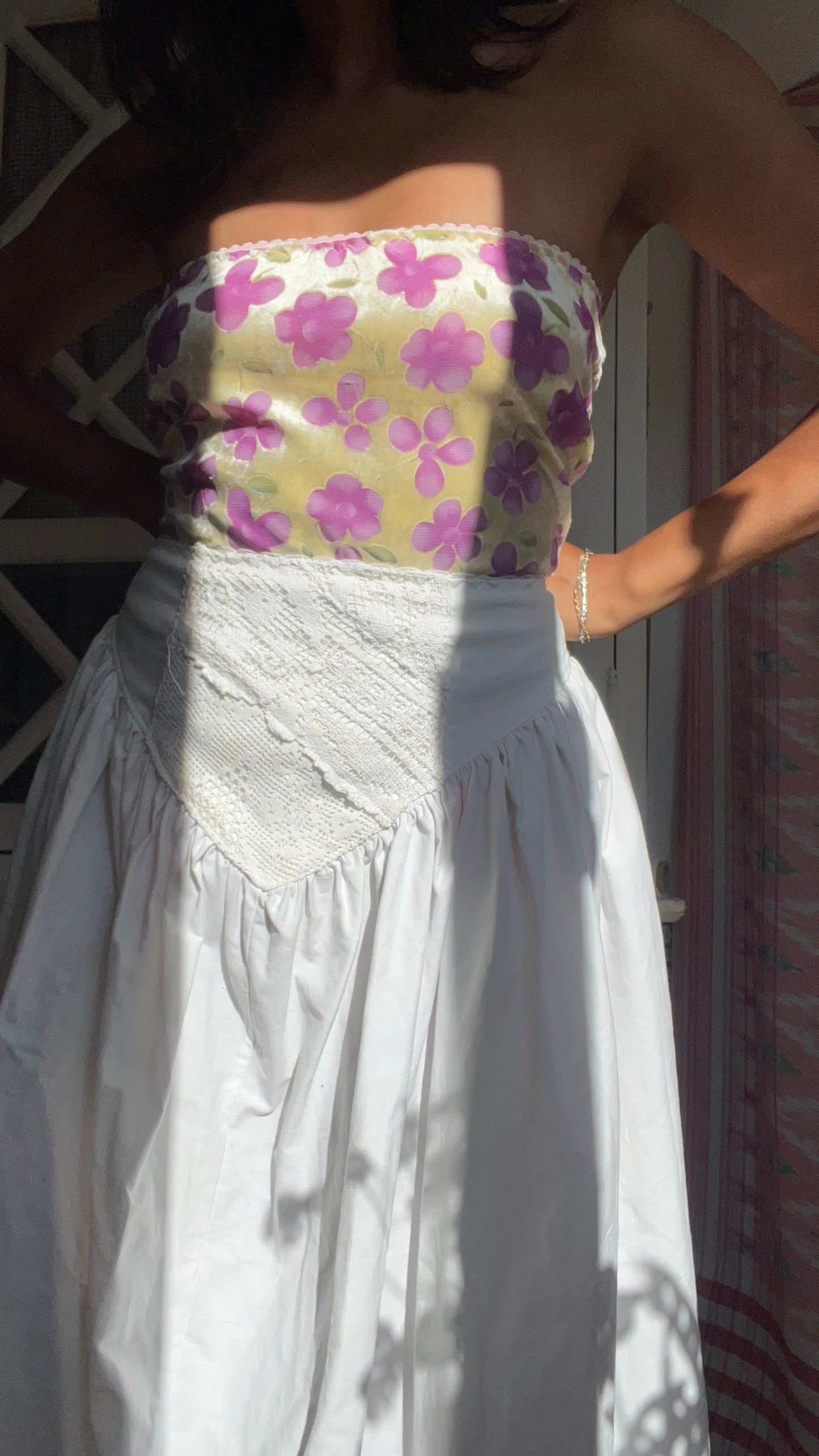 Woman wearing a strapless floral top and white skirt. Full outfit hand made by slow fashion brand Yllin