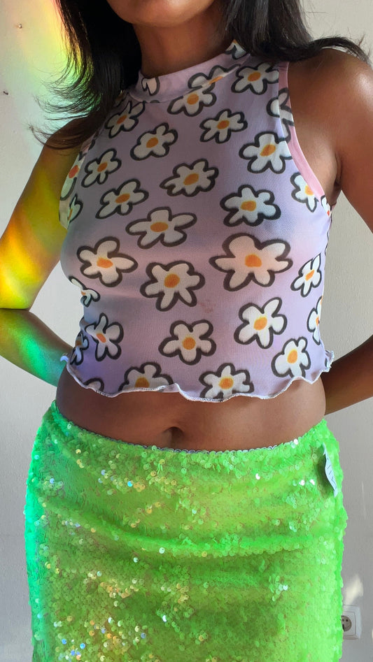 Person wearing a floral top and green skirt with a neutral background
